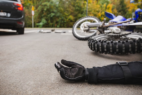 Motorcycle accident injuries in Naples, hurt motorcycle rider lying on road